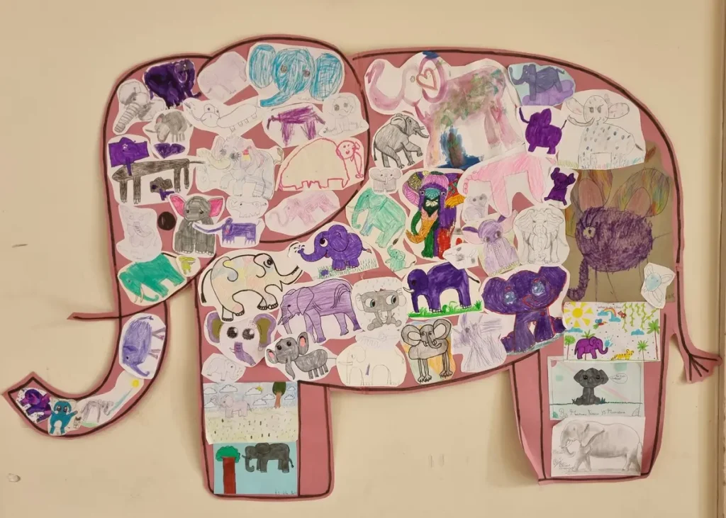 Large elephant outline on a wall, filled with various children’s elephant drawings in different styles and colours.